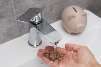 Photo of Water saving concept. Woman with coins under tap water in bathroom