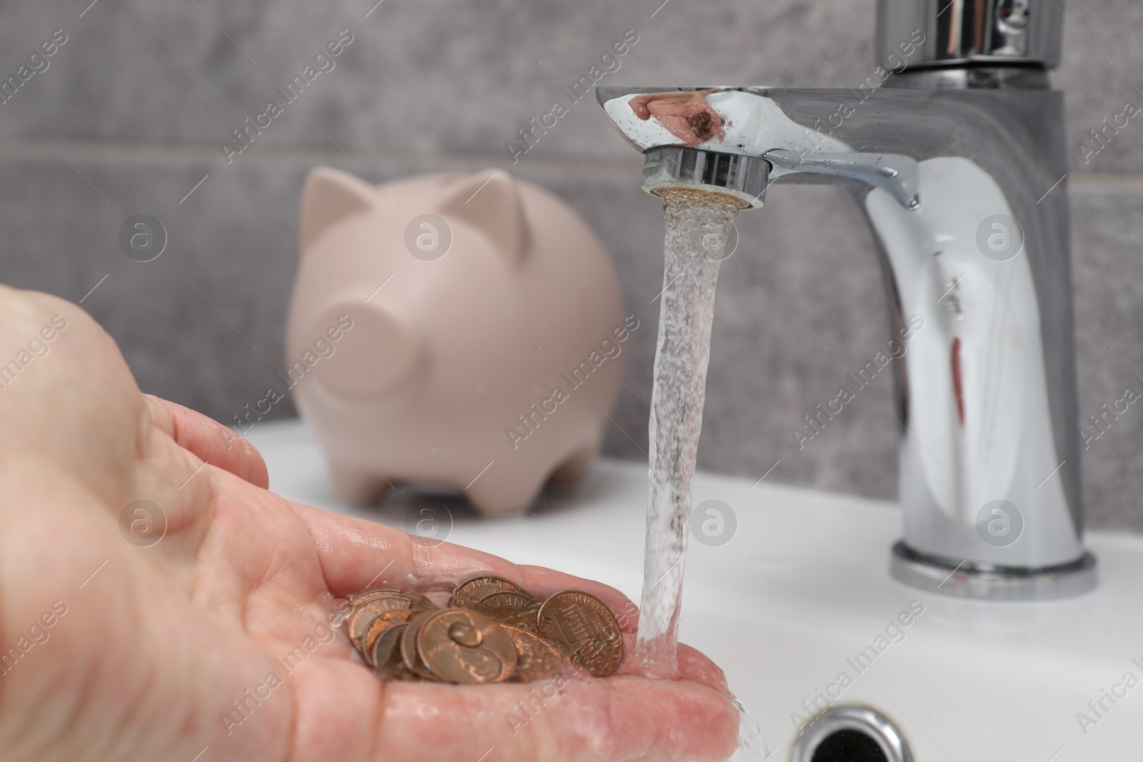 Water saving concept. Woman with coins under tap water in bathroom Photo of Water saving concept. Woman with coins under tap water in bathroom