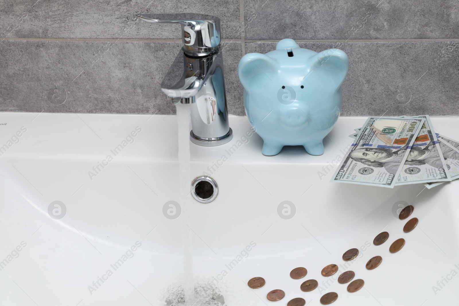 Photo of Water saving concept. Piggy bank, stream of water flowing from tap and money in bathroom