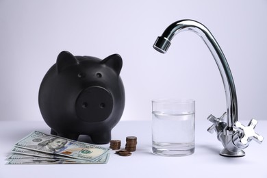 Photo of Water saving concept. Piggy bank, tap, glass of drink and money on white background