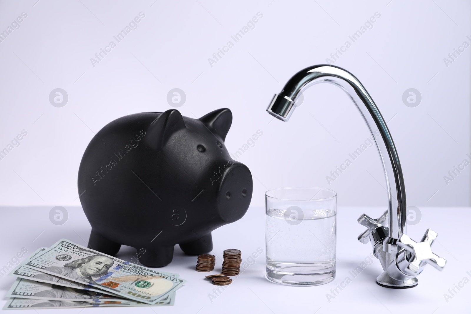 Photo of Water saving concept. Piggy bank, tap, glass of drink and money on white background