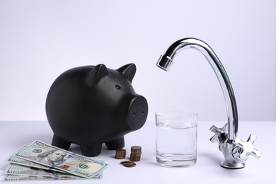 Photo of Water saving concept. Piggy bank, tap, glass of drink and money on white background