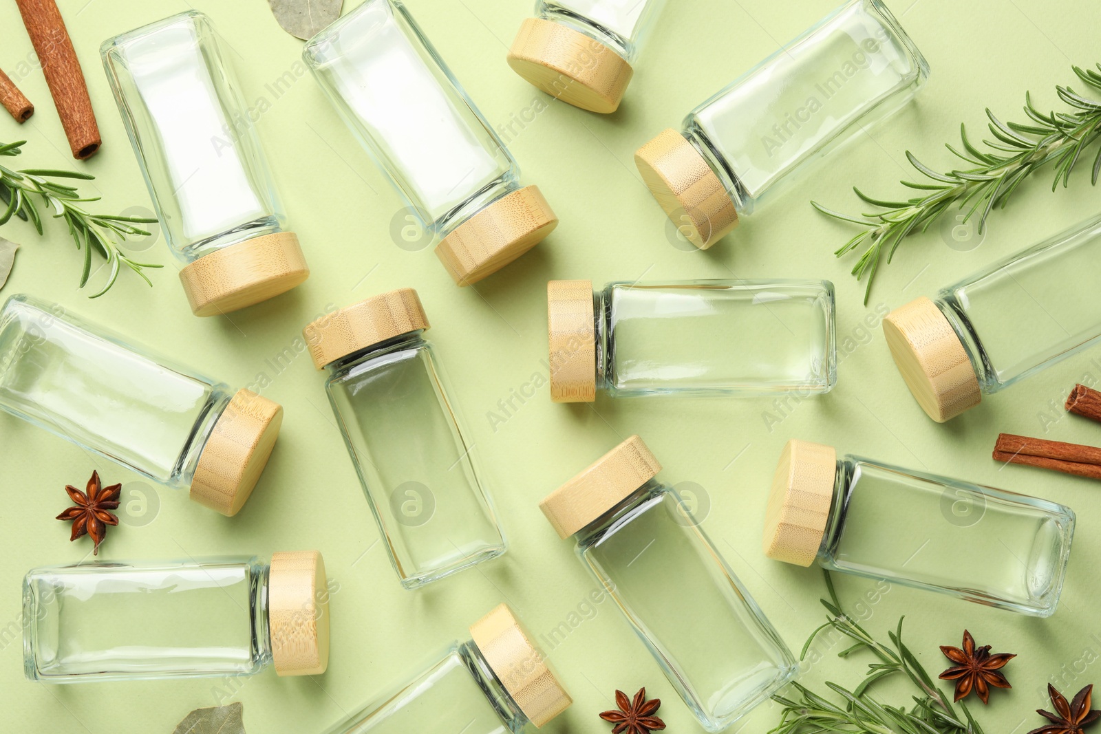 Photo of Different spices and glass jars on green background, flat lay