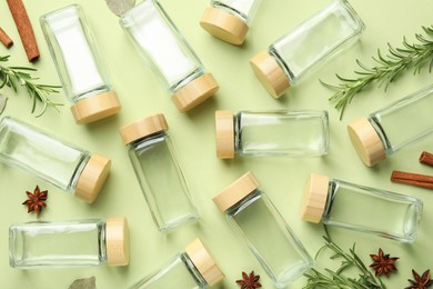 Different spices and glass jars on green background, flat lay