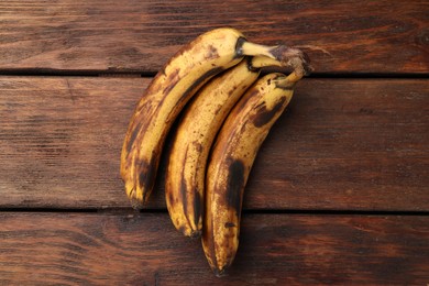 Photo of Bunch of ripe bananas with dark spots on wooden table, top view