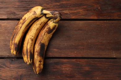 Bunch of ripe bananas with dark spots on wooden table, top view. Space for text