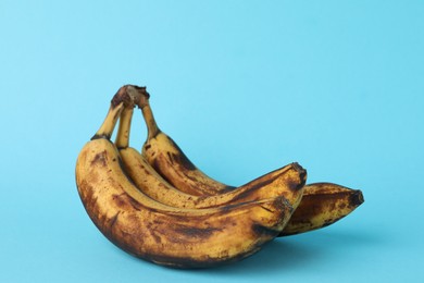 Photo of Overripe bananas with dark spots on light blue background, closeup