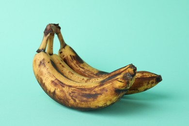 Photo of Overripe bananas with dark spots on turquoise background, closeup