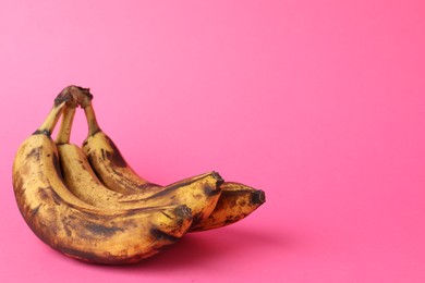 Photo of Bunch of ripe bananas with dark spots on pink background