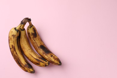 Photo of Bunch of ripe bananas with dark spots on pink background, top view. Space for text