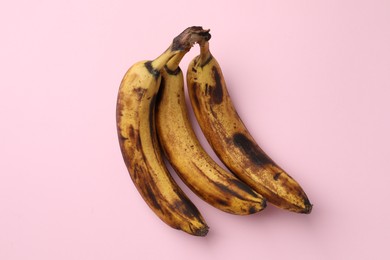 Photo of Bunch of ripe bananas with dark spots on pink background, top view