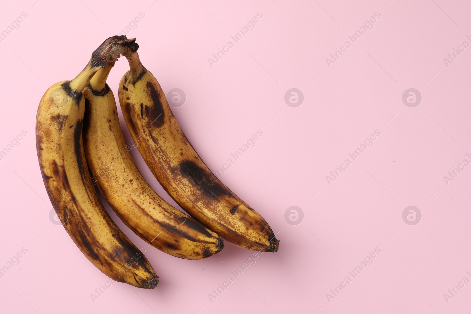 Photo of Bunch of ripe bananas with dark spots on pink background, top view. Space for text