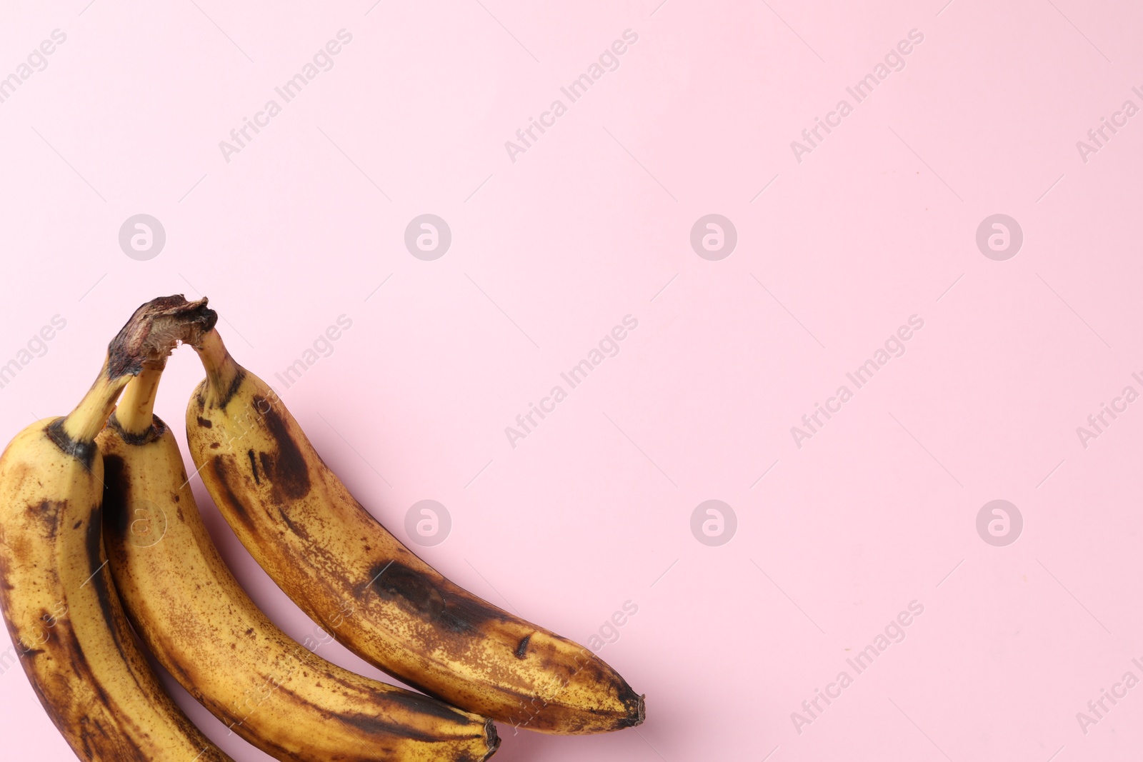 Photo of Bunch of ripe bananas with dark spots on pink background, top view. Space for text