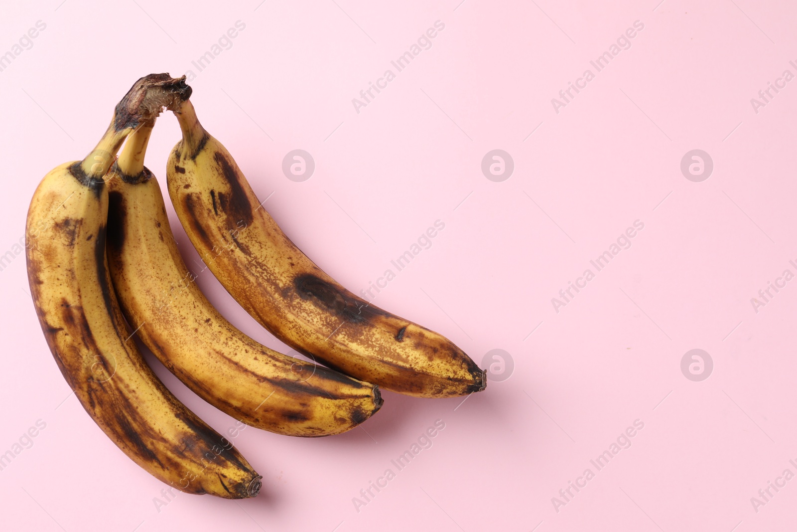 Photo of Bunch of ripe bananas with dark spots on pink background, top view. Space for text