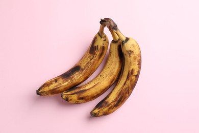 Bunch of ripe bananas with dark spots on pink background, top view