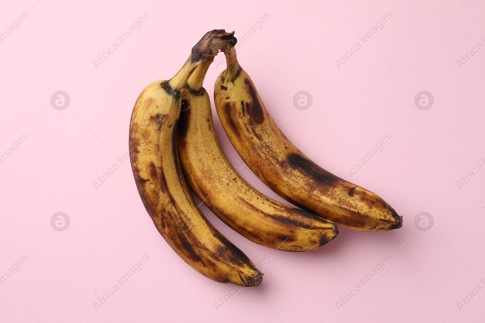 Photo of Bunch of ripe bananas with dark spots on pink background, top view