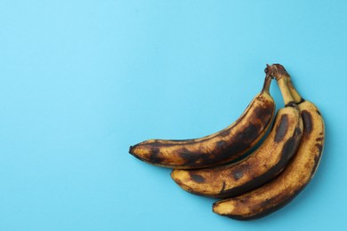 Photo of Bunch of ripe bananas with dark spots on light blue background, top view. Space for text