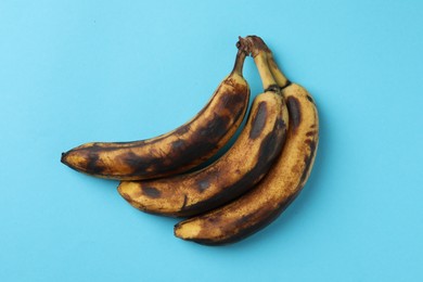 Photo of Bunch of ripe bananas with dark spots on light blue background, top view