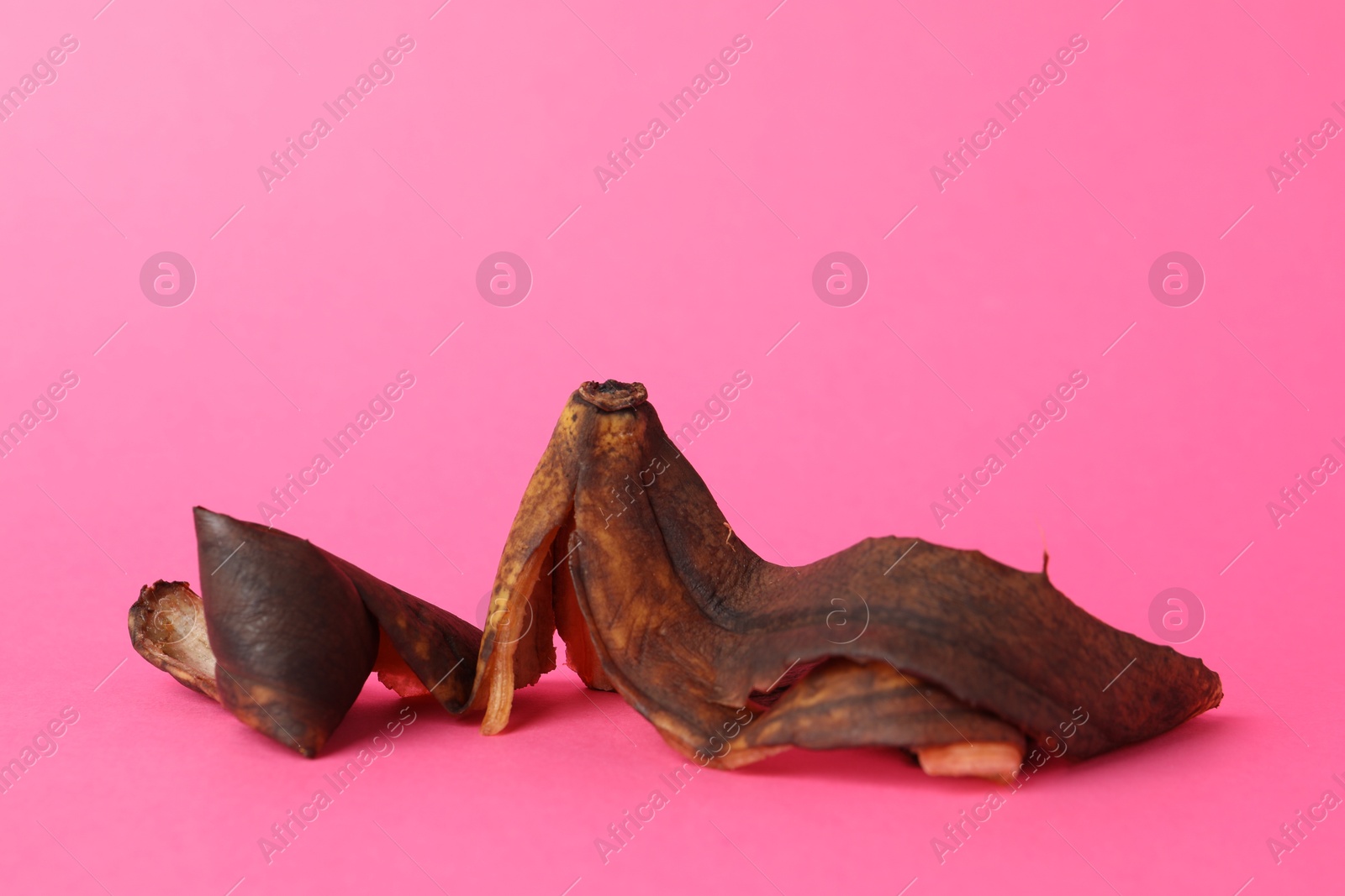 Photo of Banana peel with dark spots on pink background