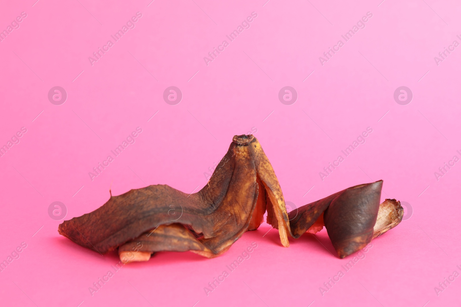 Photo of Banana peel with dark spots on pink background