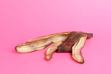 Photo of Banana peel with dark spots on pink background