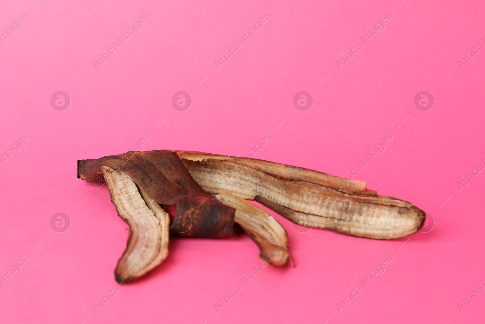 Photo of Banana peel with dark spots on pink background