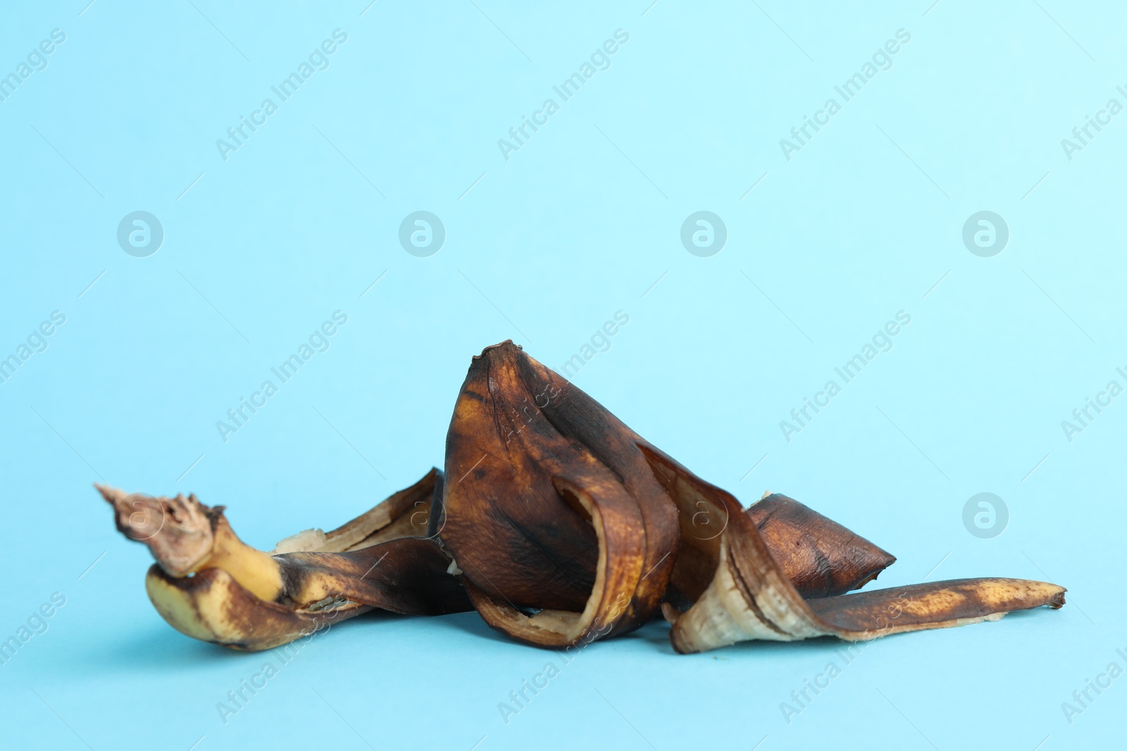 Photo of Banana peel with dark spots on light blue background