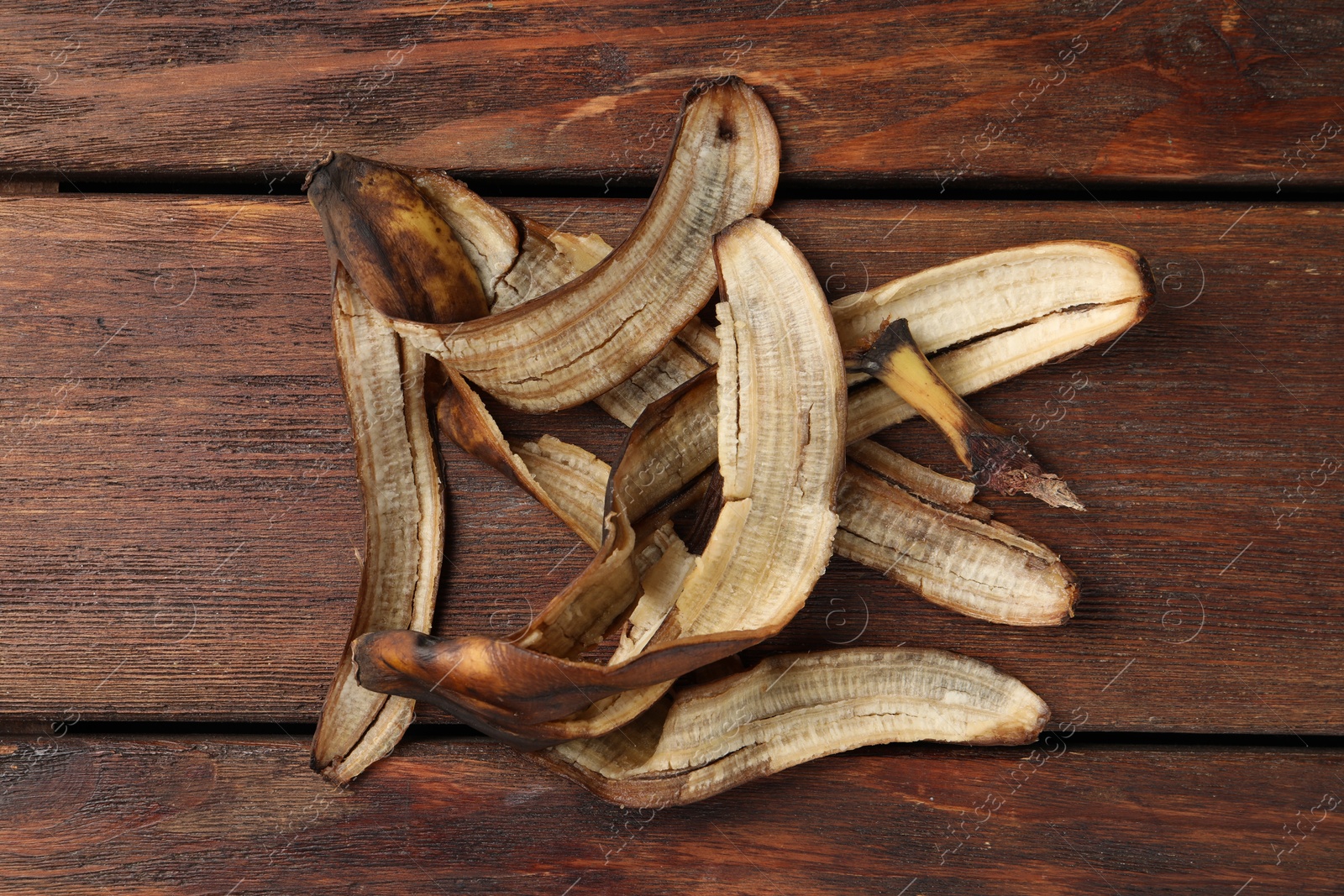 Photo of Banana peels with dark spots on wooden table, top view