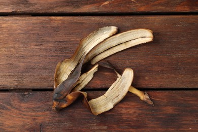 Photo of Banana peel with dark spots on wooden table, top view