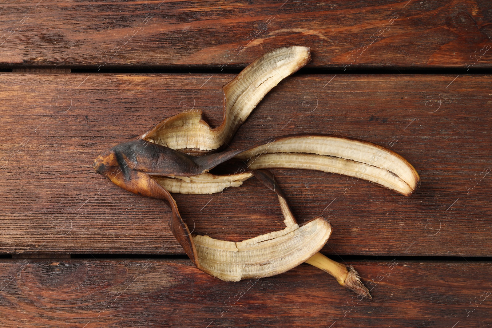 Photo of Banana peel with dark spots on wooden table, top view