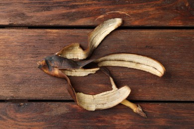 Banana peel with dark spots on wooden table, top view