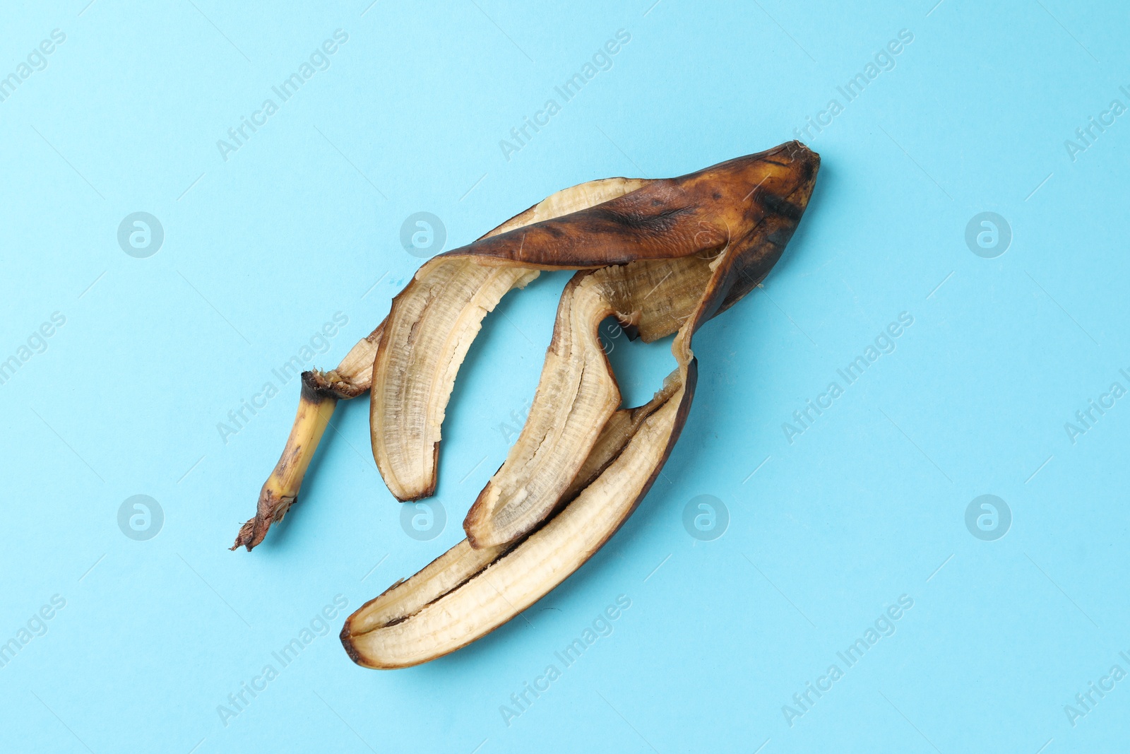 Photo of Banana peel with dark spots on light blue background, top view