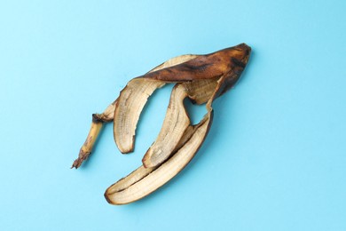 Banana peel with dark spots on light blue background, top view