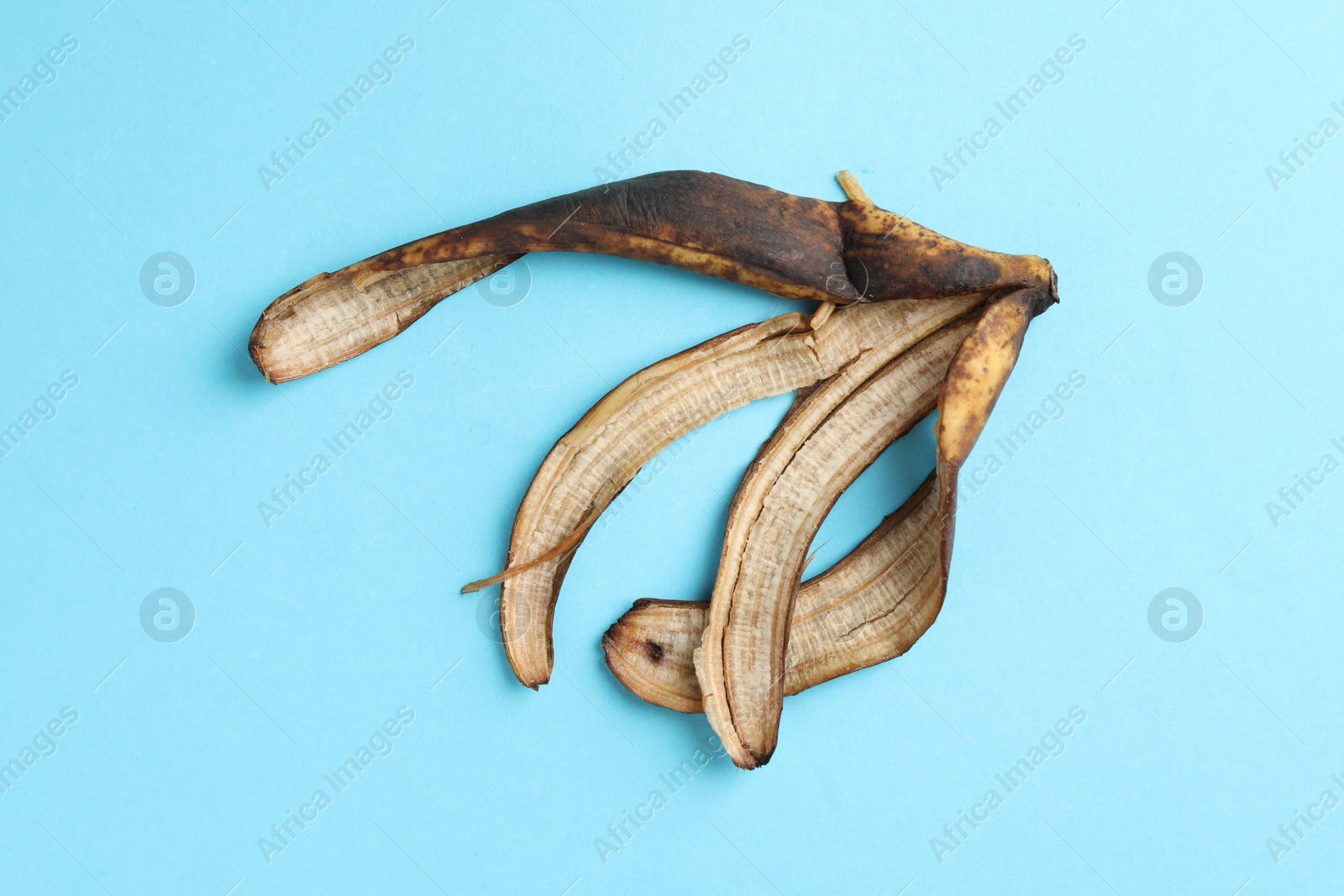 Photo of Banana peel with dark spots on light blue background, top view