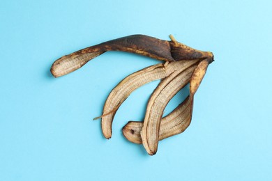 Banana peel with dark spots on light blue background, top view