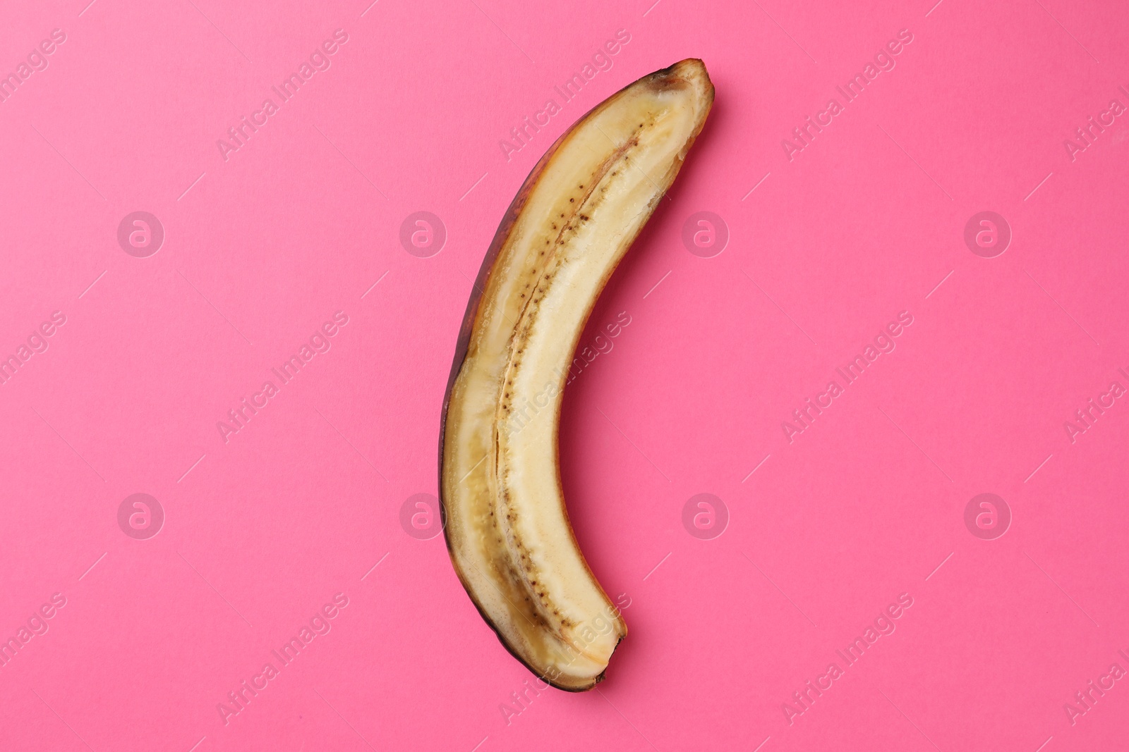 Photo of Half of overripe banana on pink background, top view