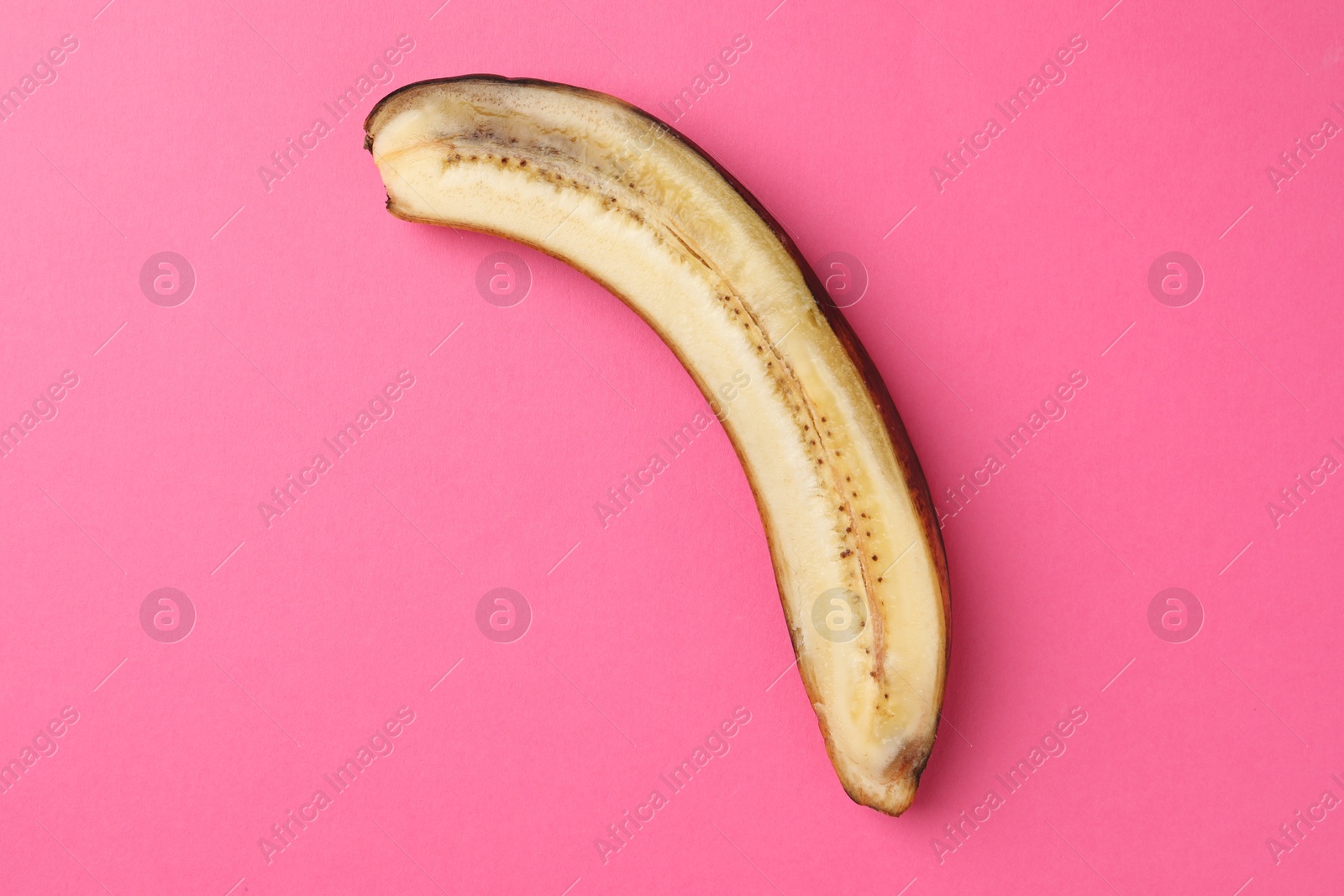 Photo of Half of overripe banana on pink background, top view