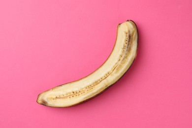 Photo of Half of overripe banana on pink background, top view