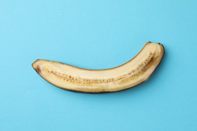 Half of overripe banana on light blue background, top view