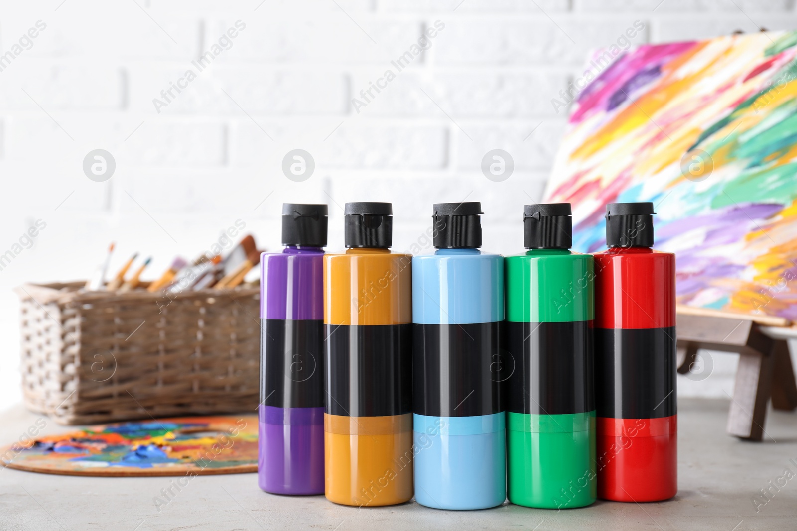 Photo of Acrylic paints of different colors in bottles on light table