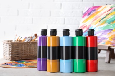 Photo of Acrylic paints of different colors in bottles on light table