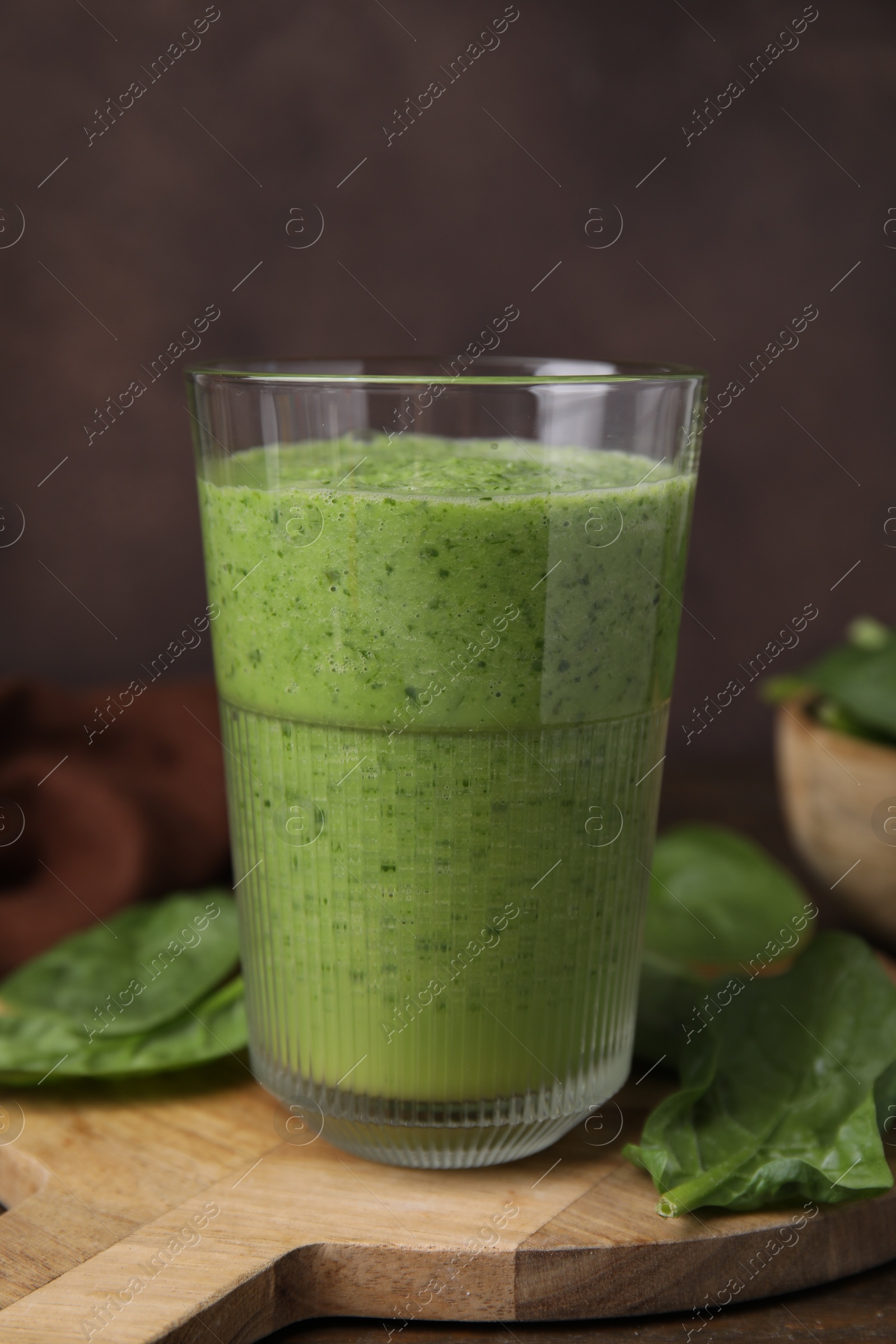 Photo of Tasty green smoothie in glass and spinach on table, closeup