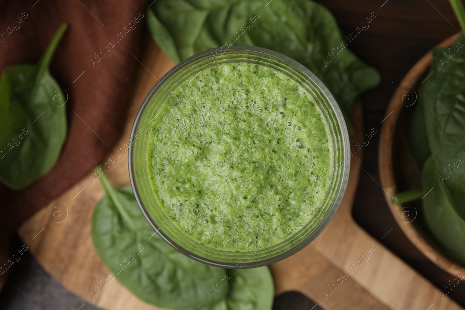 Photo of Tasty green smoothie in glass and spinach on table, flat lay