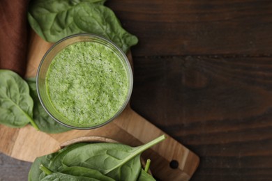 Tasty green smoothie in glass and spinach on wooden table, flat lay. Space for text