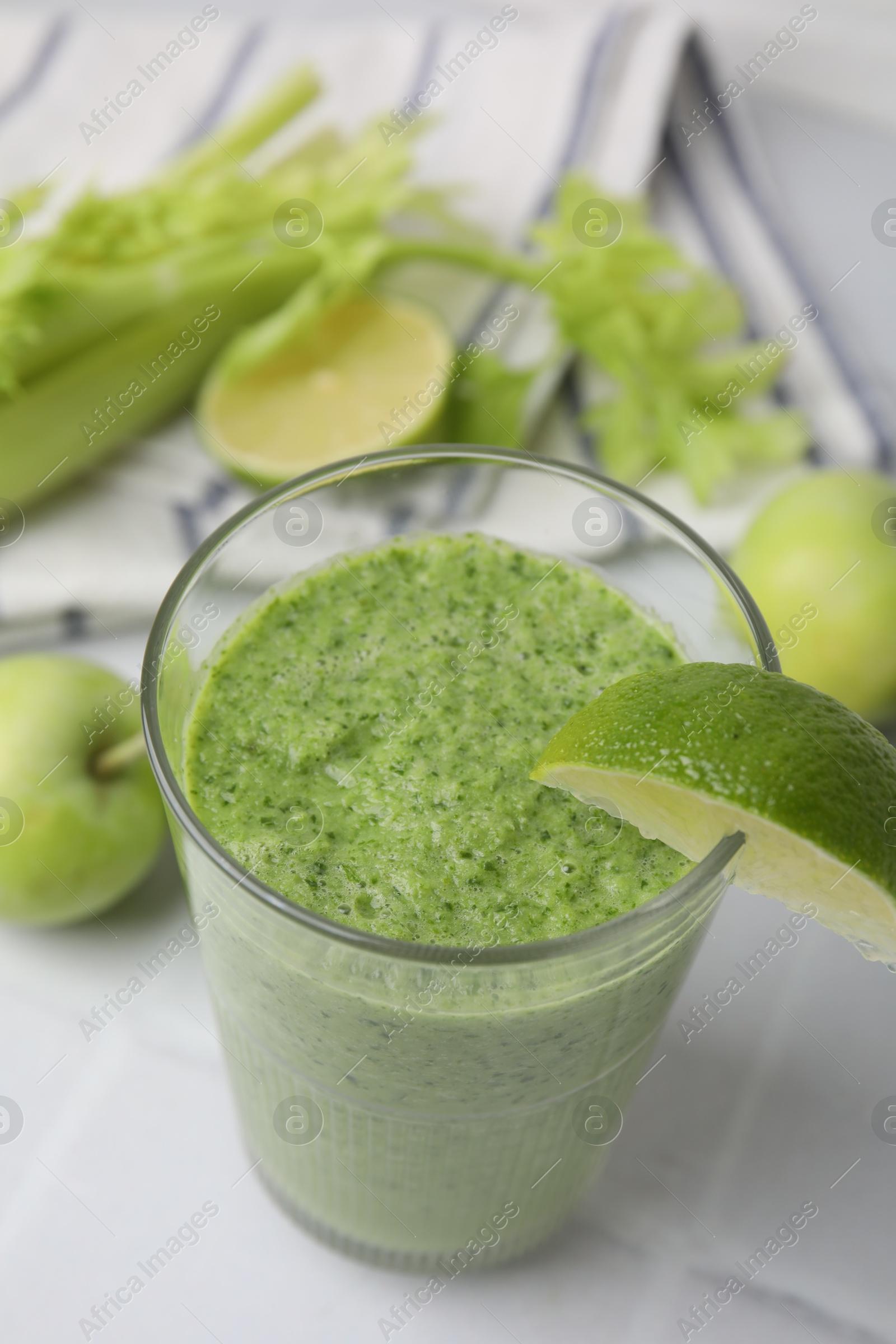 Photo of Tasty green smoothie in glass with lime on white tiled table, above view