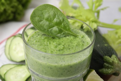 Photo of Tasty green smoothie in glass, lime and vegetables on table, closeup