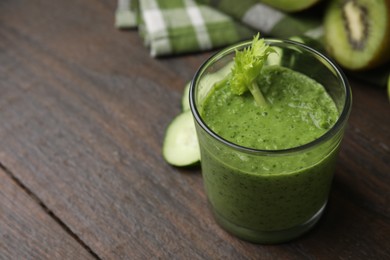 Photo of Tasty green smoothie in glass on wooden table, closeup. Space for text