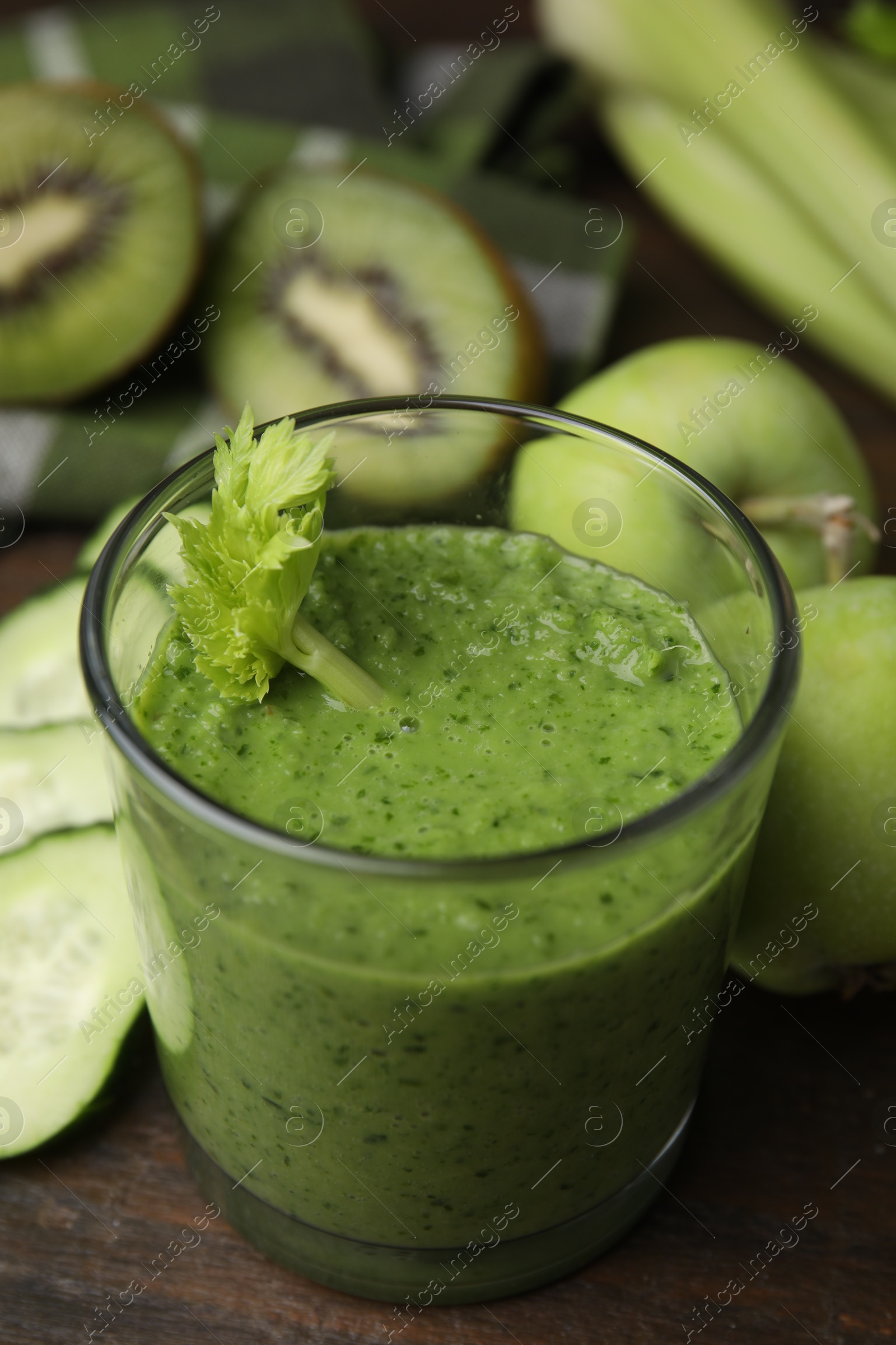 Photo of Tasty green smoothie in glass and products on wooden table, closeup