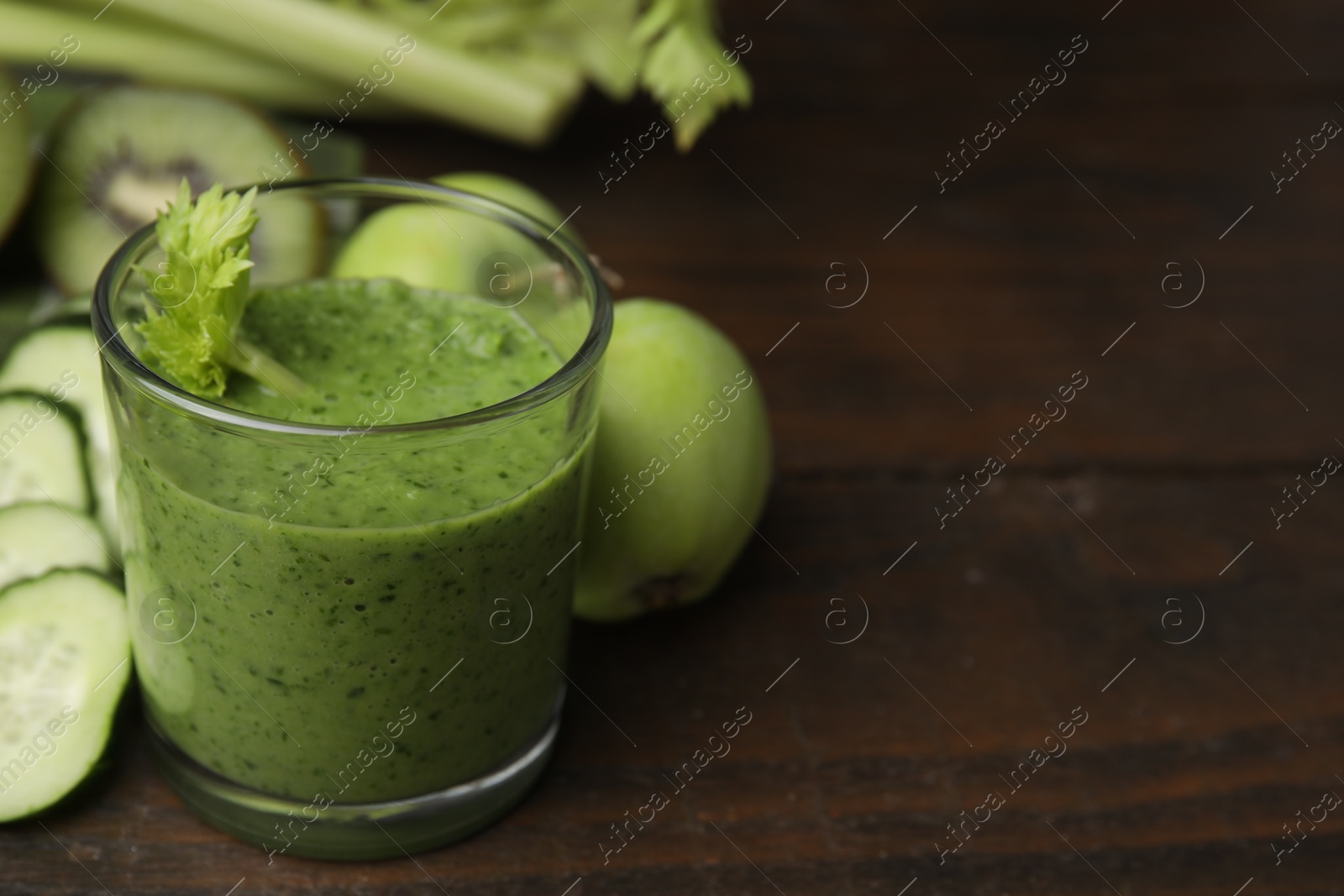 Photo of Tasty green smoothie in glass and products on wooden table, closeup. Space for text