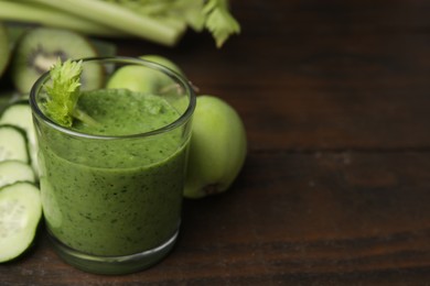 Tasty green smoothie in glass and products on wooden table, closeup. Space for text